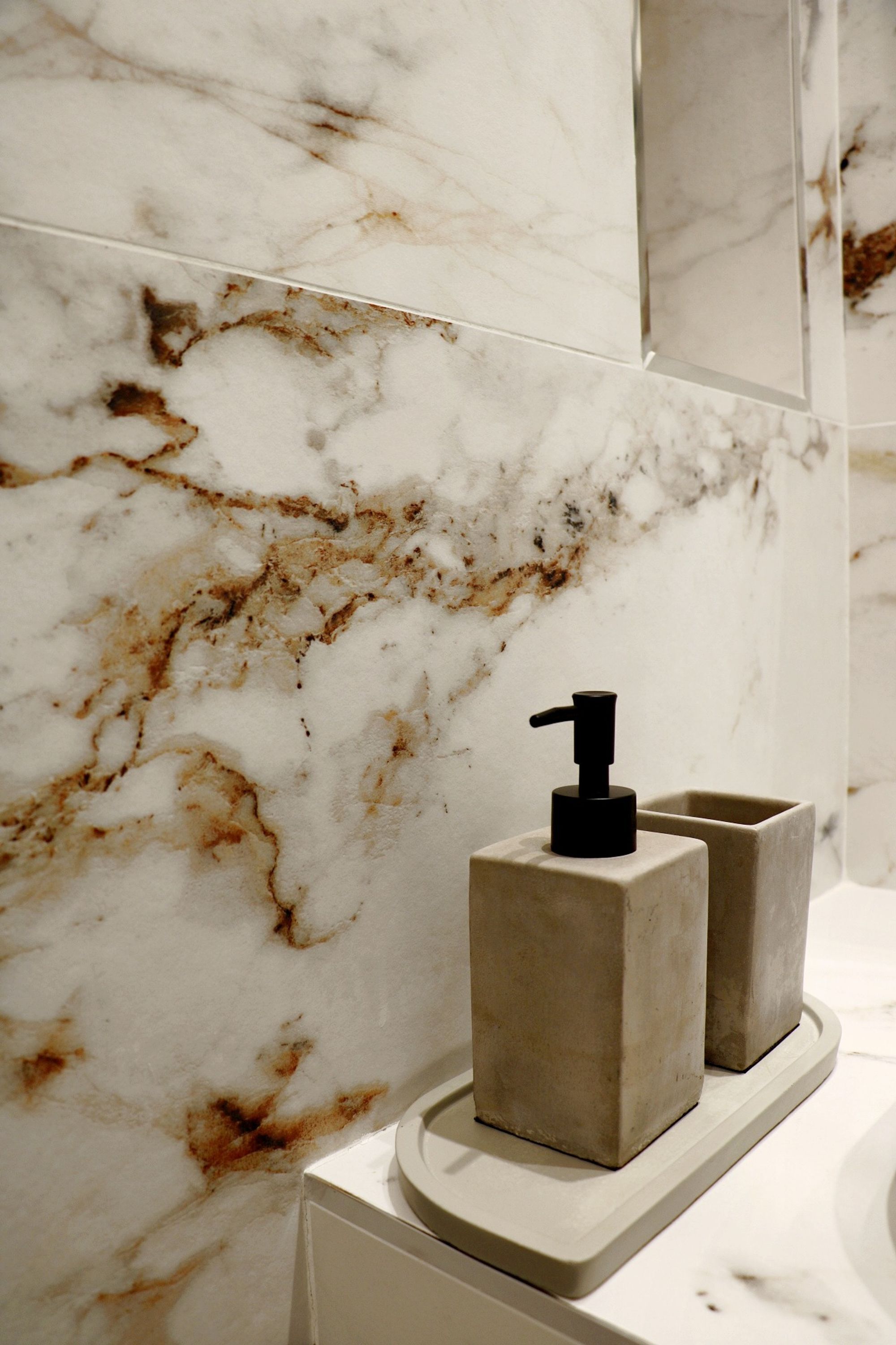 A bathroom with marble walls and a modern faucet.