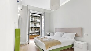 A modern bedroom with a green bed frame, white bedding, a bedside table, and a view of a balcony with a railing. - Lepetit 3 Welcomely - Two Bedroom Apartment, Sleeps 5 (Milan)