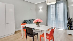 A modern dining area with a white table, black and orange chairs, and a vase of flowers. - Lepetit 3 Welcomely - Two Bedroom Apartment, Sleeps 5 (Milan)