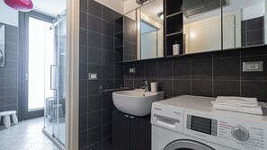 A modern bathroom with a Bosch washing machine, a sink, and a glass shower enclosure. - Italianway Easy - Segesta 3 (San Siro)