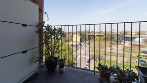 A balcony with potted plants, a view of a parking lot, and buildings in the background. - Italianway Easy - Segesta 3 (San Siro)
