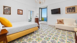 A bedroom with a bed, a sofa, a TV, and a balcony. - Mimosa Room Sea View (Torre Elisabetta) (Massa Lubrense)