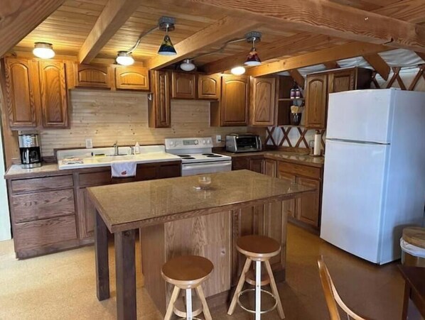 Kitchen area with stove, microwave, refrigerator, and seating at the central island.