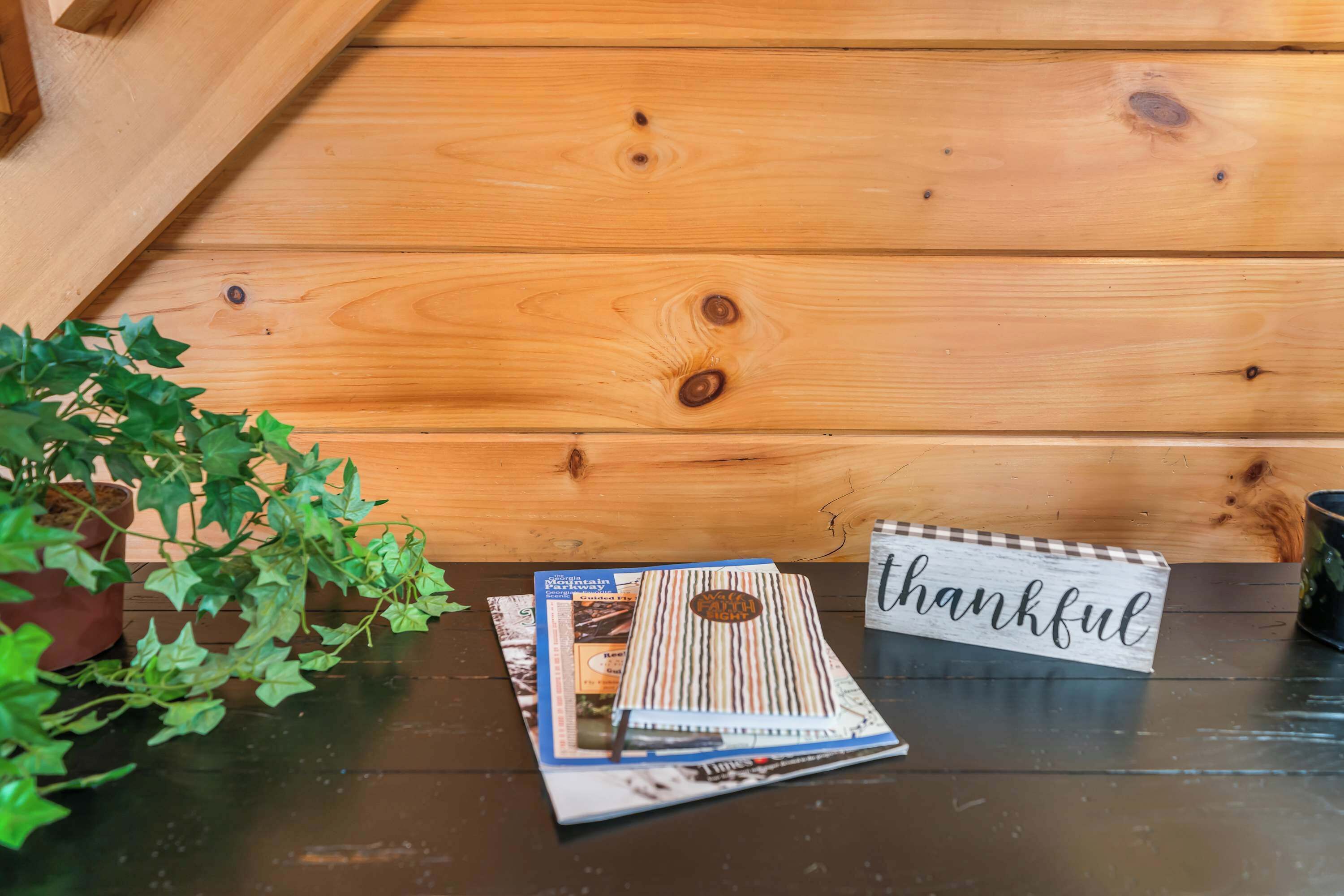 A wooden table with a 'thankful' sign, a notebook, and a potted plant.
