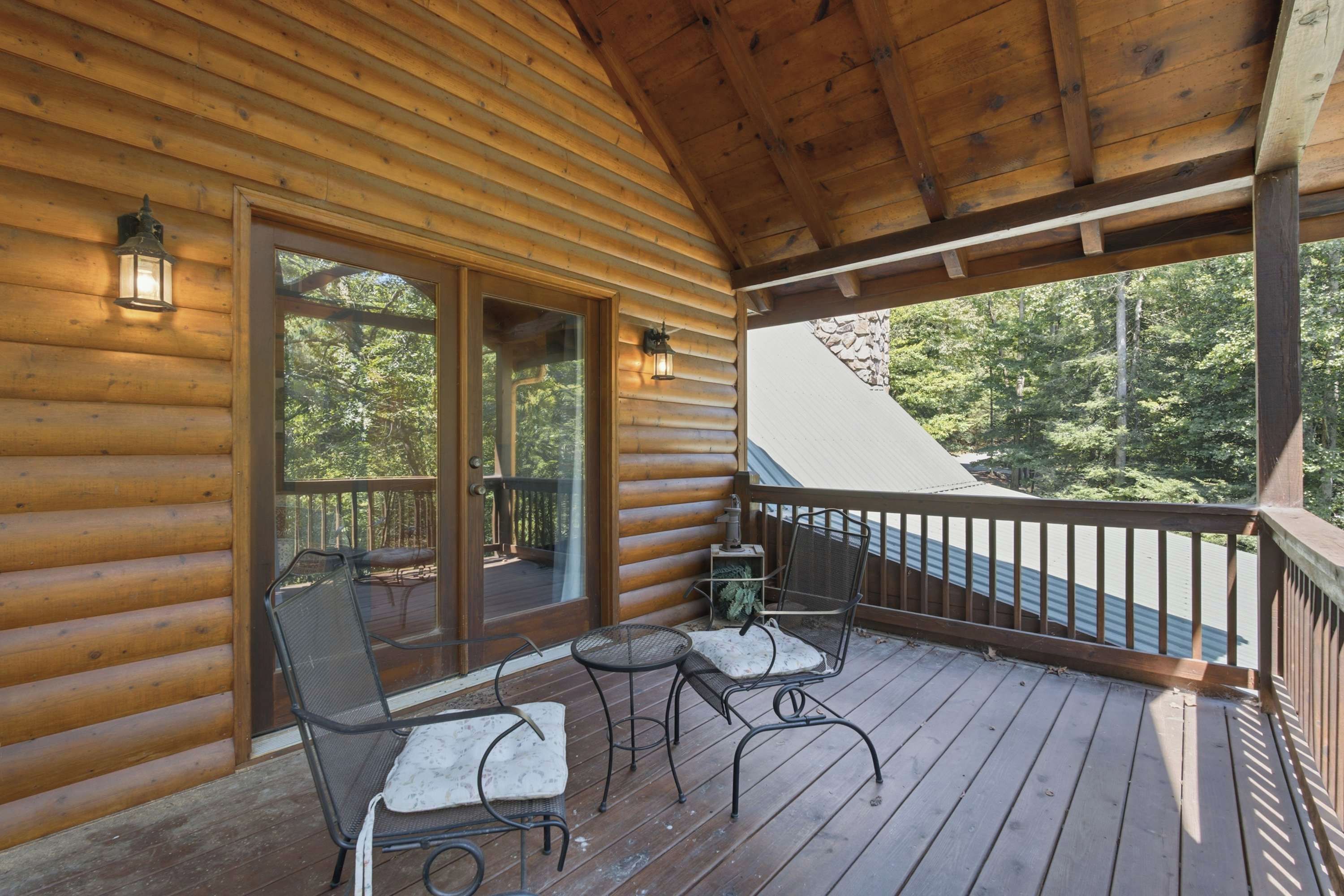 A wooden cabin with a covered porch featuring two chairs and a small table.