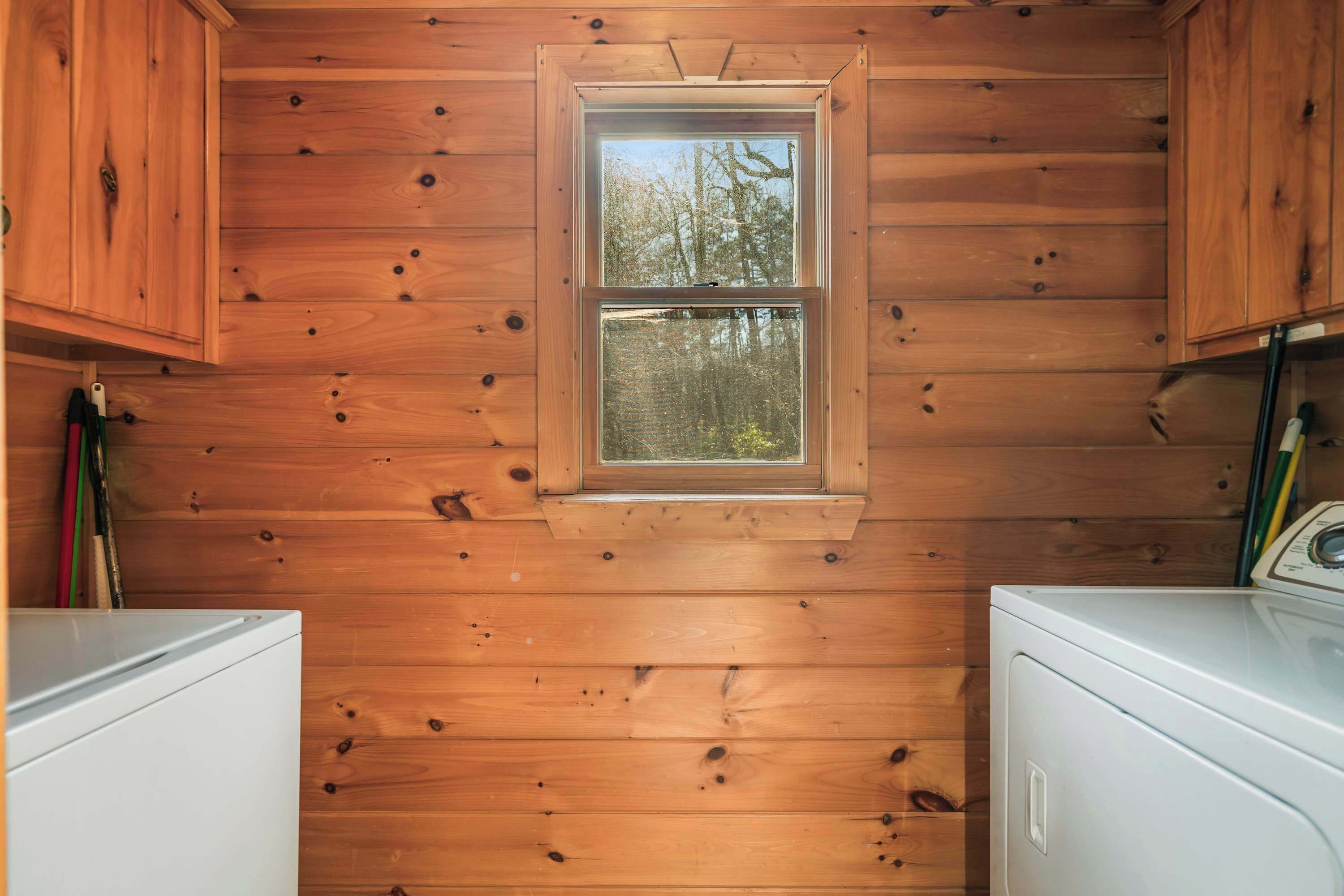 Ein Holzblock-Innenraum mit Fenster, zwei weiße Waschmaschinen und Holzschränken.