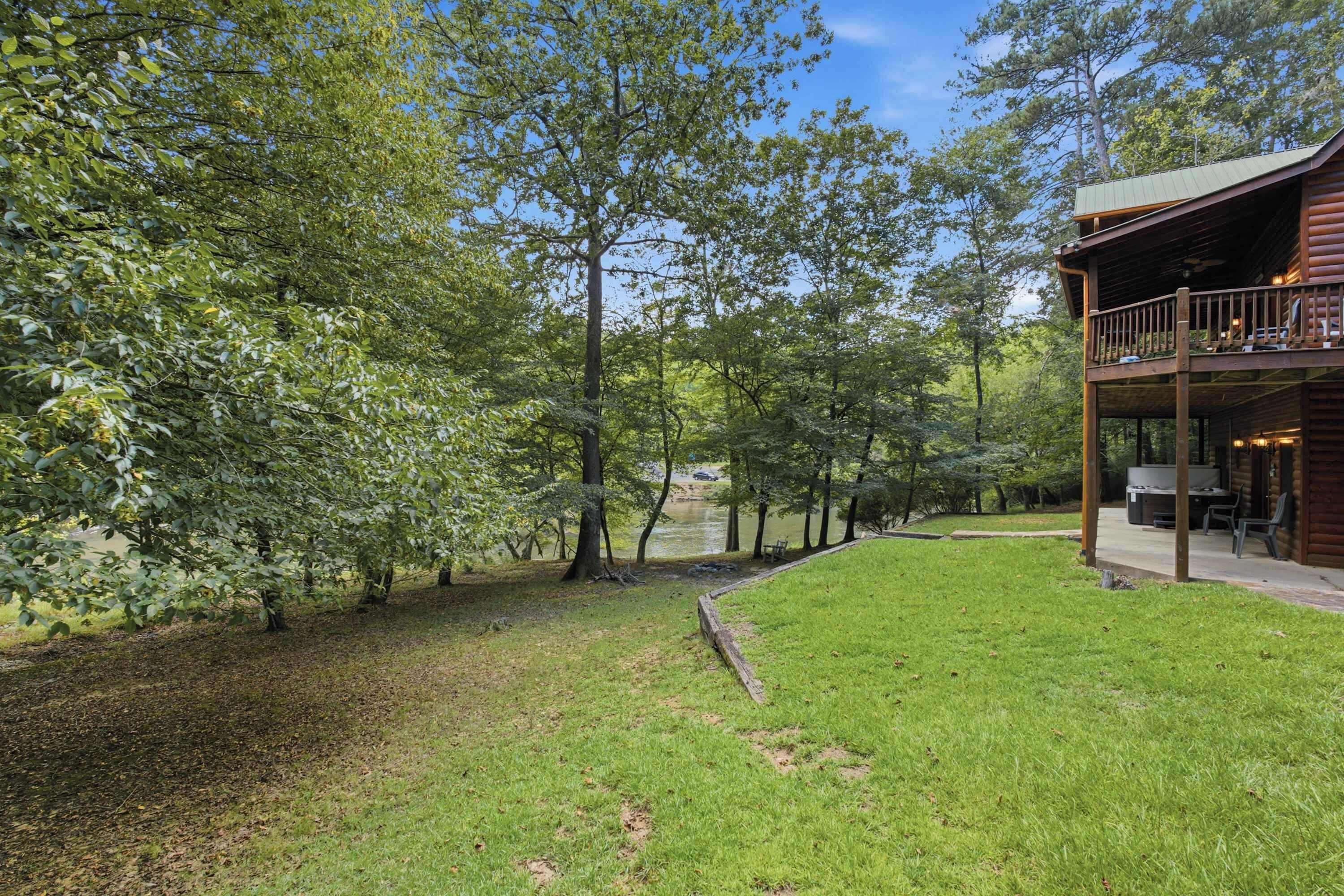 Une cabane en bois dotée d’une terrasse et de meubles d’extérieur, entourée d’une pelouse et d’arbres.