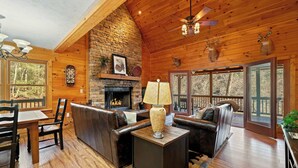 A cozy cabin interior with a fireplace, leather furniture, and wooden walls. - New! Riverfront Retreat Sleeps 12 Ellijay (Ellijay)