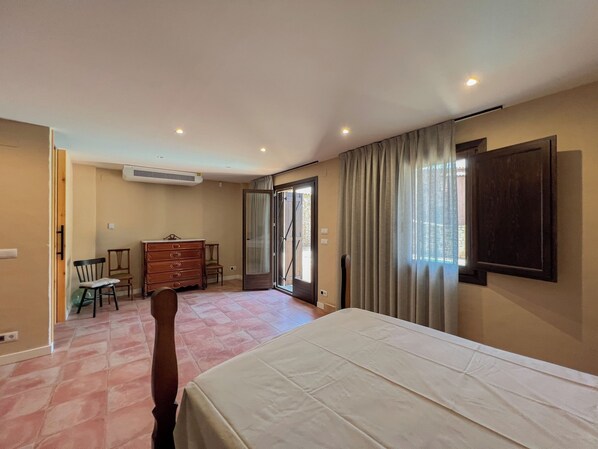 A bedroom with a bed, a dresser, a chair, and a sliding glass door leading to a balcony.