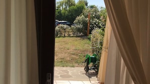 A view through a doorway into a courtyard with a tiled floor, a hanging lantern, and a green garden hose. - Residenze del Mare (Porto Ottiolu)