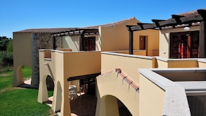 A building with a stone facade, a tiled roof, and a covered patio area with outdoor seating. - Residenze del Mare (Porto Ottiolu)