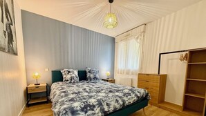Une chambre à coucher avec un lit, des tables de chevet, une armoire et une fenêtre avec des rideaux.