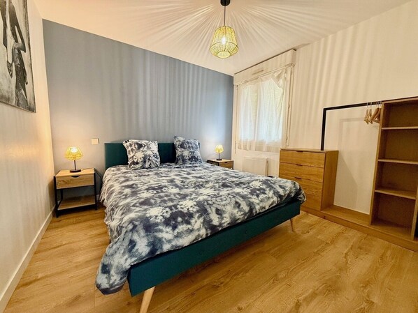 Une chambre à coucher avec un lit, des tables de chevet, une armoire et une fenêtre avec des rideaux.