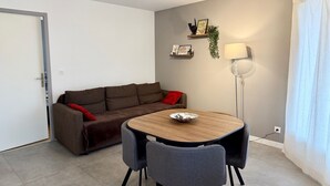 Un salon moderne avec un canapé marron, une table de salle à manger ronde en bois et deux chaises grises.
