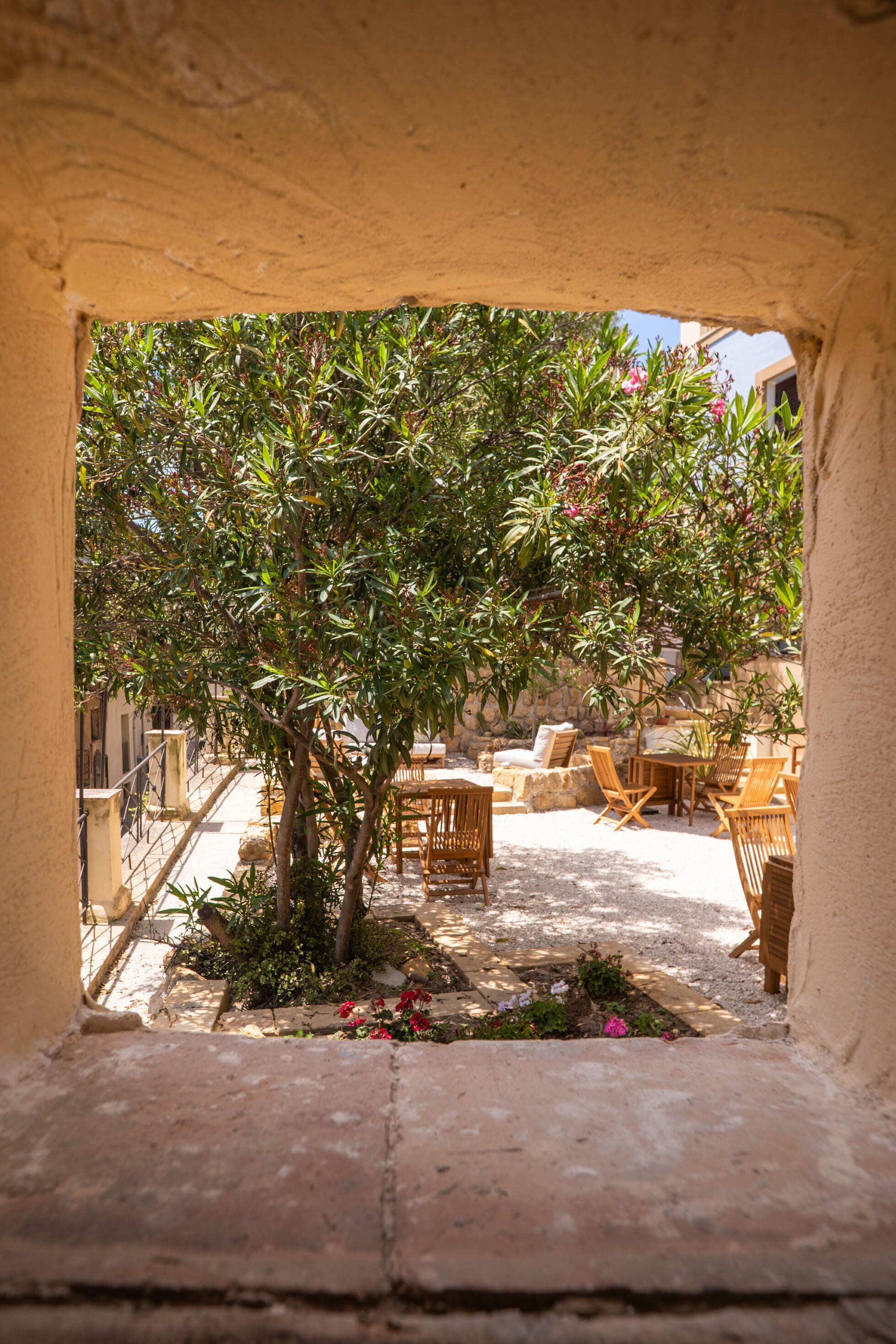 Un patio con un árbol, asientos al aire libre y un muro de piedra.