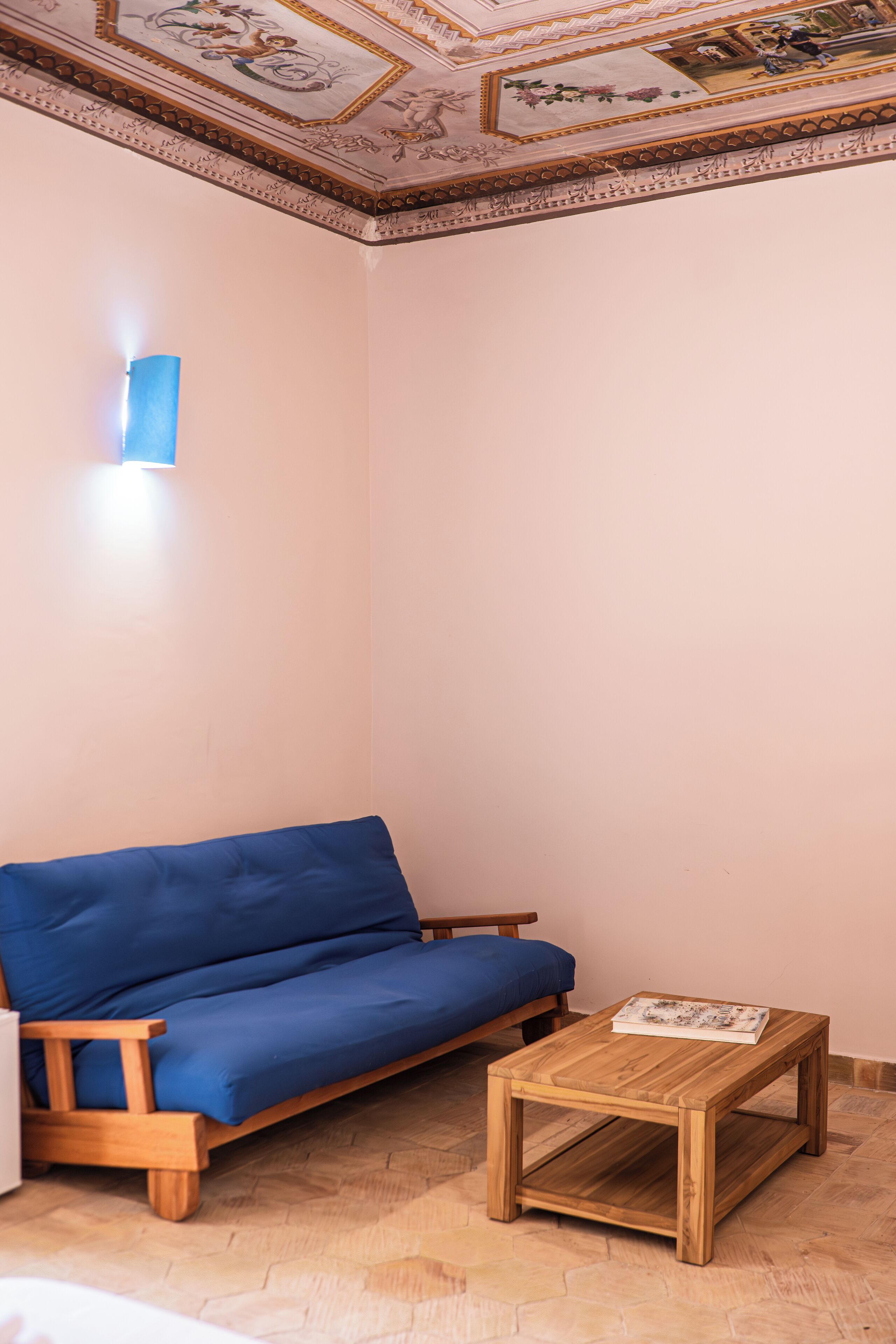 Une pièce avec un canapé en bois, une petite table en bois et un plafond décoratif.
