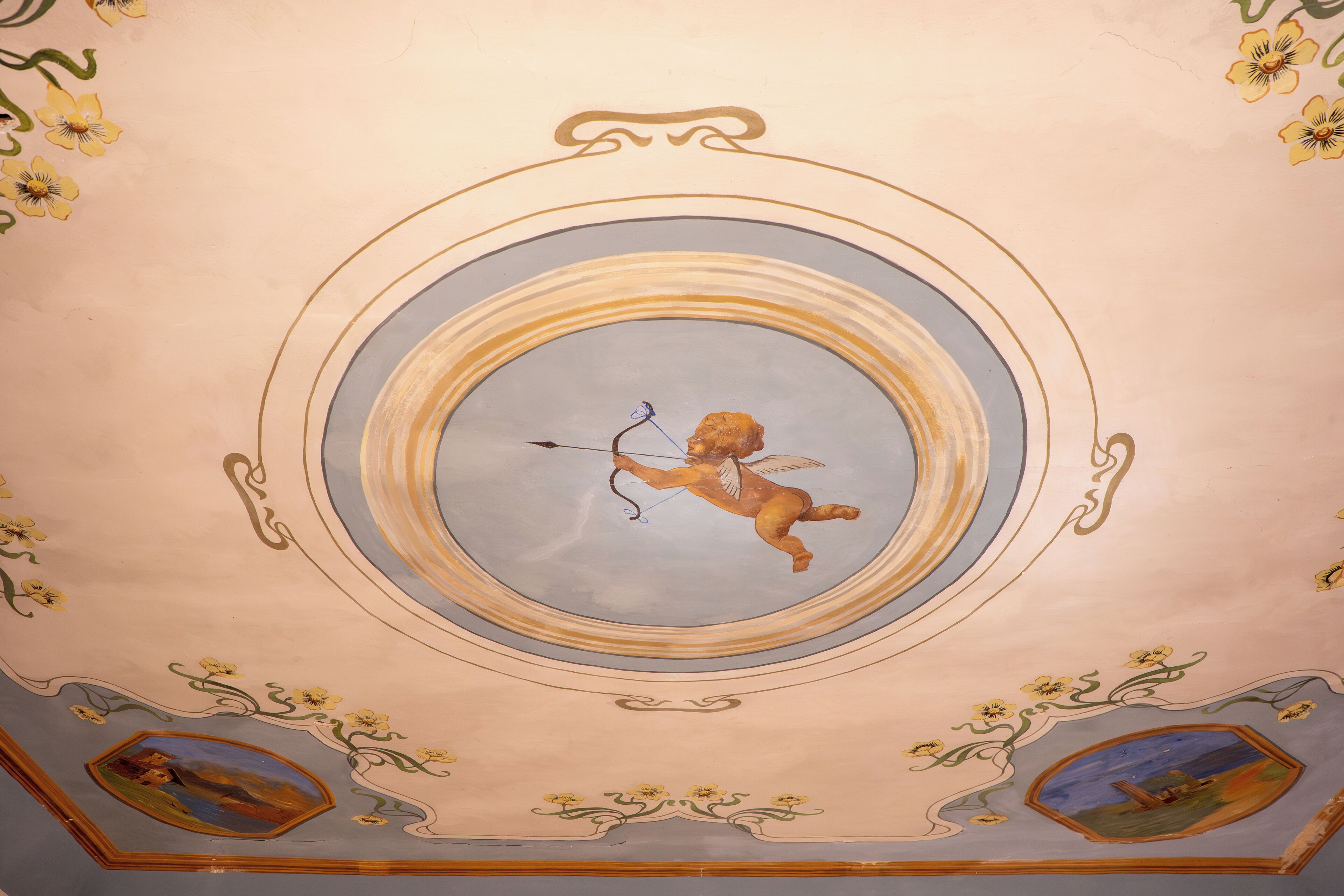 A ceiling with a central circular design featuring a cherub holding a bow.