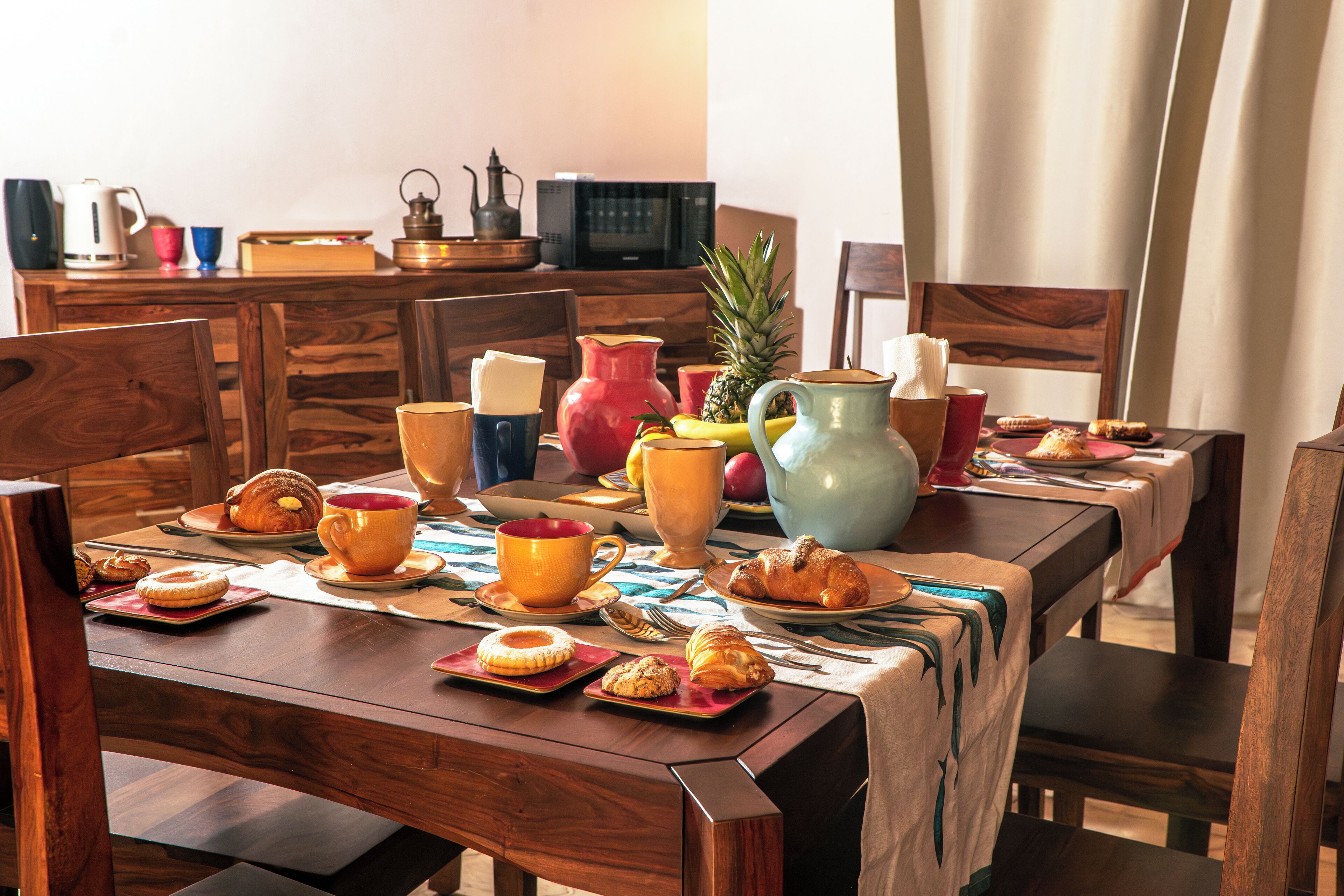 A breakfast table set with pastries, mugs, and a pitcher.