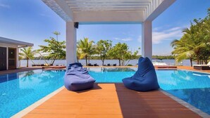 A poolside area with two bean bags, wooden deck, and a view of the sea. - Houseboats By DAE Colombo (Piliyandala)