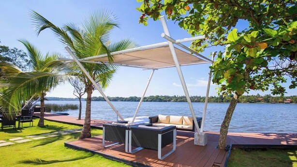 A deck with outdoor seating and a canopy, overlooking a body of water. - Houseboats By DAE Colombo (Piliyandala)