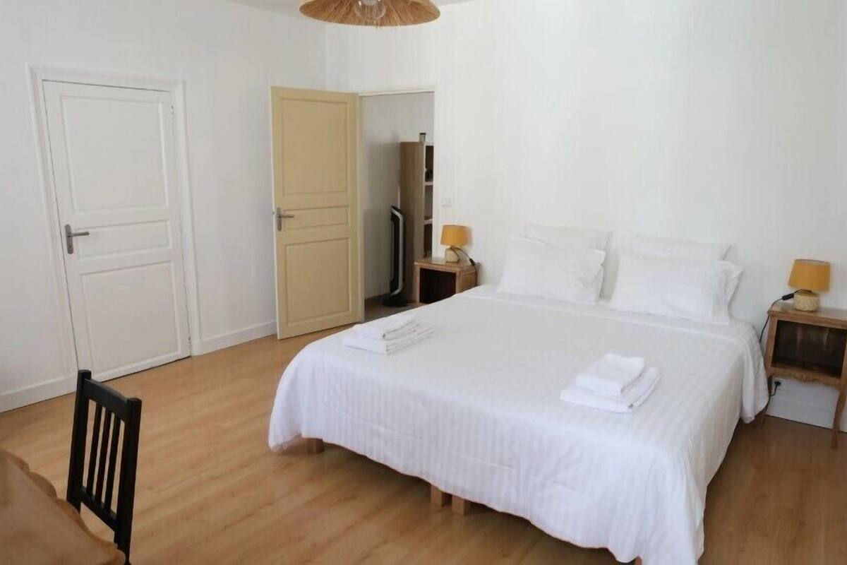Une chambre à coucher comprenant un lit, deux tables de chevet, une chaise et une armoire.