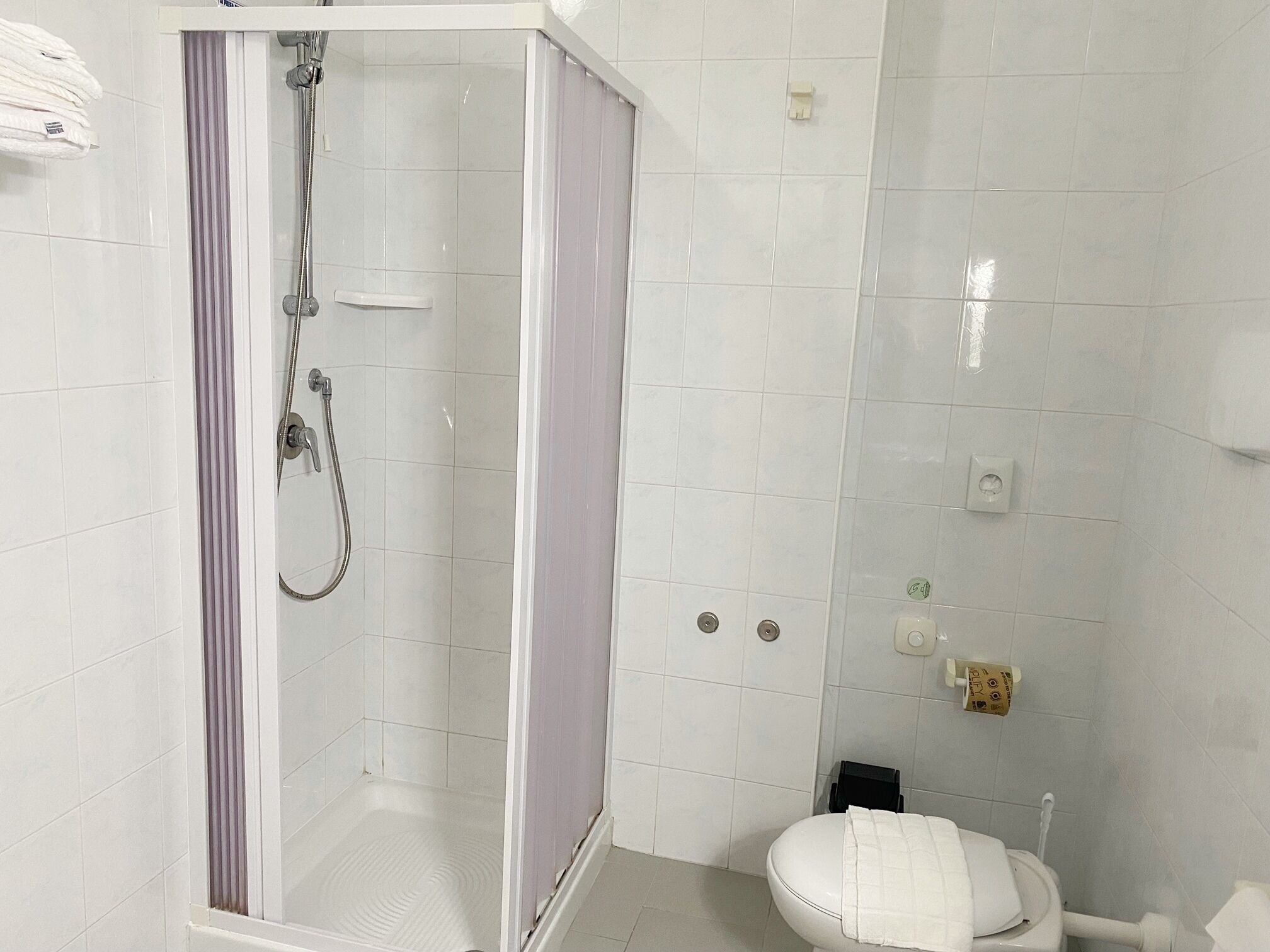 Une salle de bain moderne avec une douche à parois de verre, des carreaux blancs, des toilettes et un porte-serviettes.