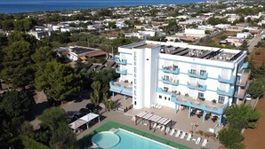 A multi-story hotel with balconies, a swimming pool, and a view of the sea. - Hotel Villaggio Aurora (Manduria)
