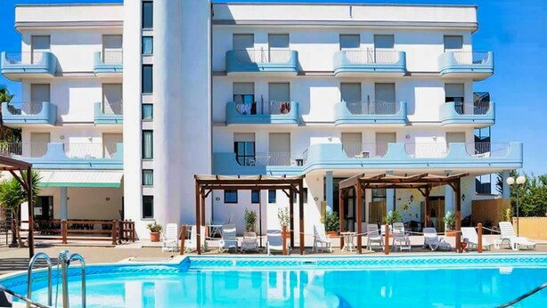 A multi-story hotel with balconies, a swimming pool, and outdoor seating areas. - Hotel Villaggio Aurora (Manduria)
