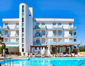 A multi-story hotel with balconies, a swimming pool, and outdoor seating areas.