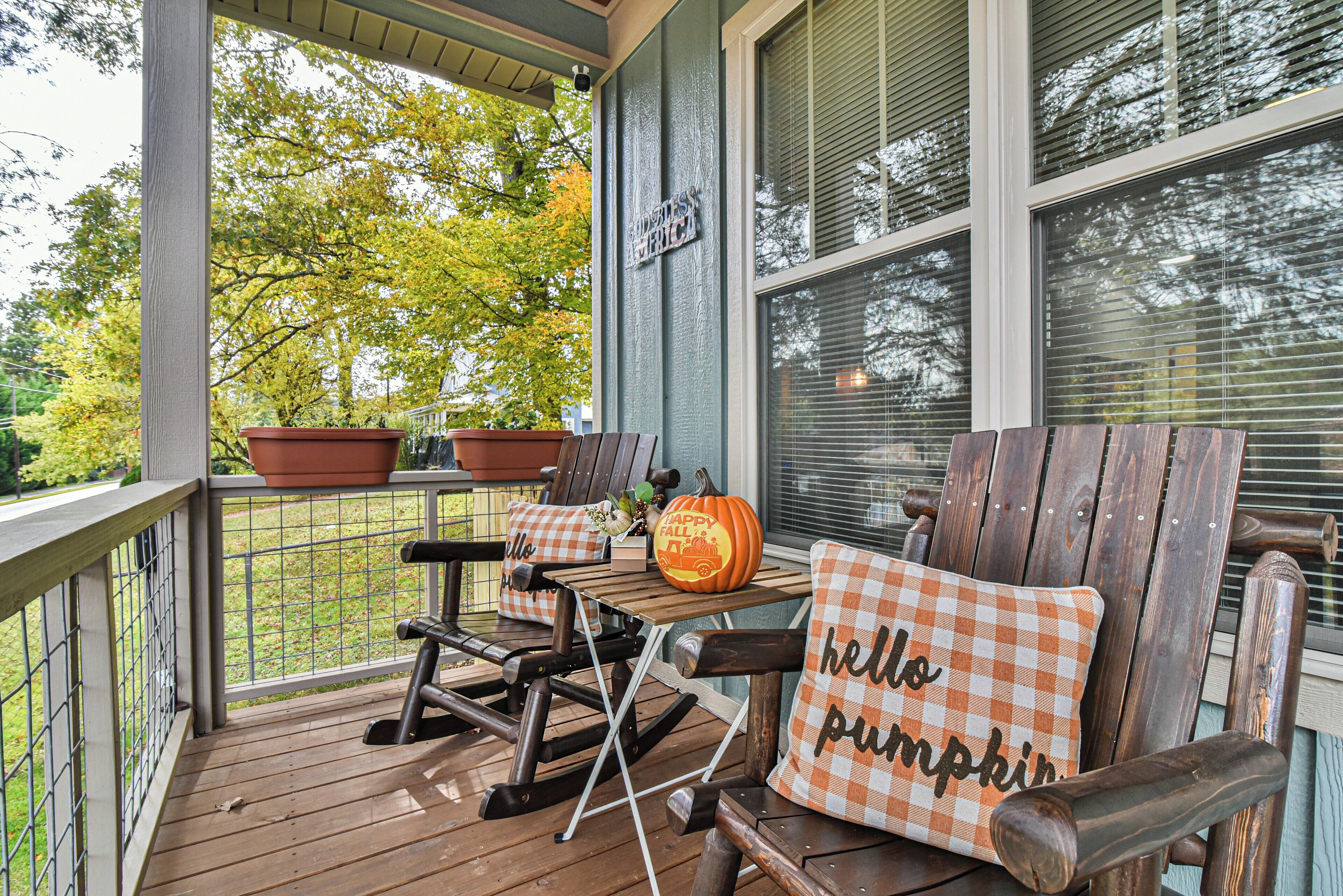 A porch with rocking chairs, a table, and potted plants.