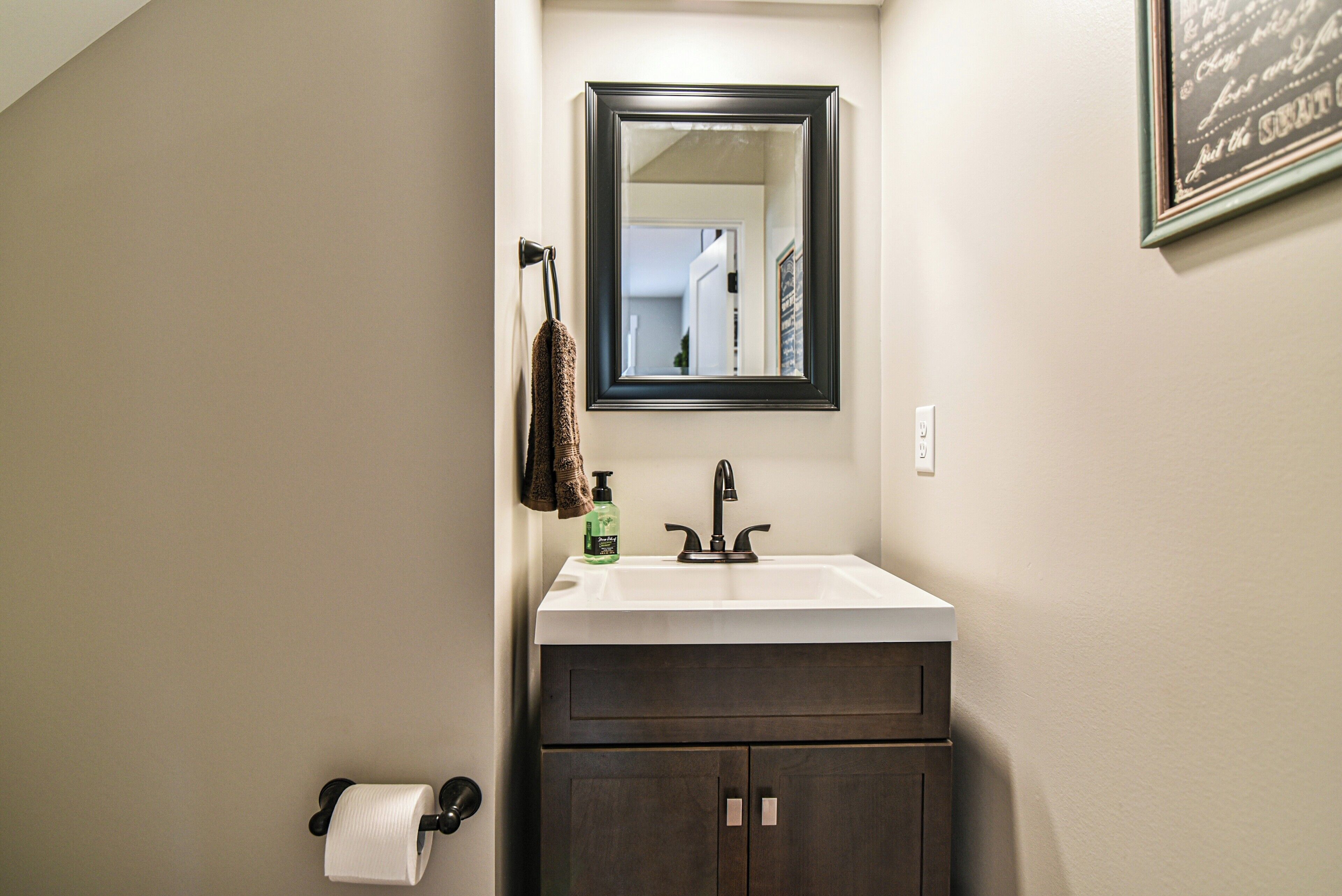 A bathroom with a dark wood vanity, a white sink, a mirror, and a towel rack.