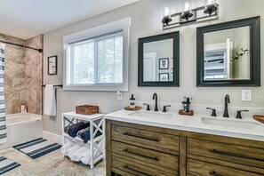 A bathroom with a bathtub, double sink vanity, and a large mirror. - The Montreat House (Black Mountain)