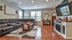A spacious living room with a large sectional sofa, a coffee table, and a flat-screen TV mounted on the wall. - The Montreat House (Black Mountain)