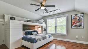 A bedroom with a loft bed, a ceiling fan, a large window, and a poster on the wall. - The Montreat House (Black Mountain)