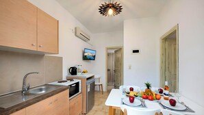 Een moderne keuken met een ingebouwde oven, magnetron en spoelbak. Er staat een eettafel gedekt met borden, bestek en een schaal fruit.