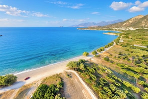 Eine Küstenlandschaft mit freiem Blick auf das Meer, einem Sandstrand und terrassierten Feldern.