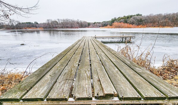 A wooden pier extending into a frozen lake with a bench at the end. - Lake Cabin | Sauna · River · Game Room (Brodhead)