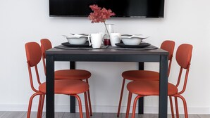 A modern dining area with a black table, red chairs, and a TV displaying "NETFLIX". - Family - by Kairos Apartments (Gliwice)