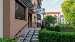 A residential building with a staircase leading to a balcony, surrounded by greenery. - Family - by Kairos Apartments (Gliwice)