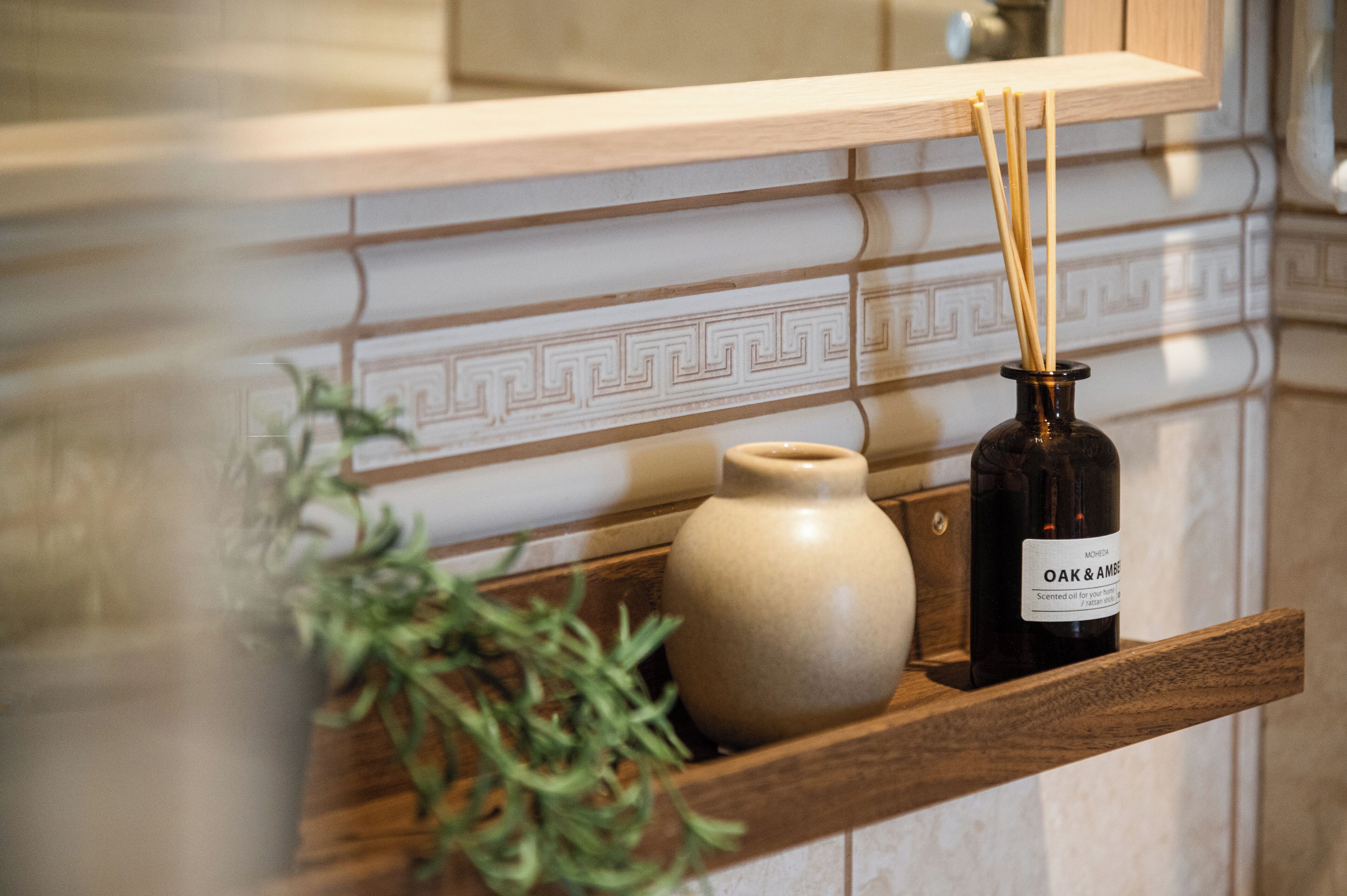 Een houten plank met een keramieken vaas en een fles OAK & AMBER geurolie.