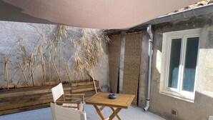Un patio con una mesa y sillas de madera, una ventana y una planta en maceta.
