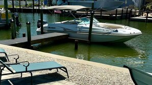 A marina with a boat docked at a wooden pier, a pool area with lounge chairs, and modern buildings in the background. - Stay and Play by the Bay 
Boaters Delight. Waterfront ,Dockage and Heated Pool

 (Fort Myers Beach)