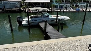 A marina with docked boats, a house with a balcony, and a palm tree. - Stay and Play by the Bay 
Boaters Delight. Waterfront ,Dockage and Heated Pool

 (Fort Myers Beach)