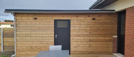 A wooden exterior with a black door and a small table in front.