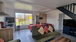 Amplia sala de estar con sofá, mesa de comedor y zona de cocina con refrigerador y microondas.