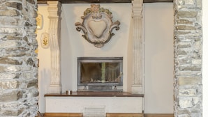Une cheminée ornée d’un cadre en forme de cœur, flanquée de murs en pierre et surmontée d’une cheminée en bois.