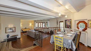 Une salle à manger spacieuse avec un plafond haut, une table à manger dressée pour quatre personnes et une vue sur le salon attenant.