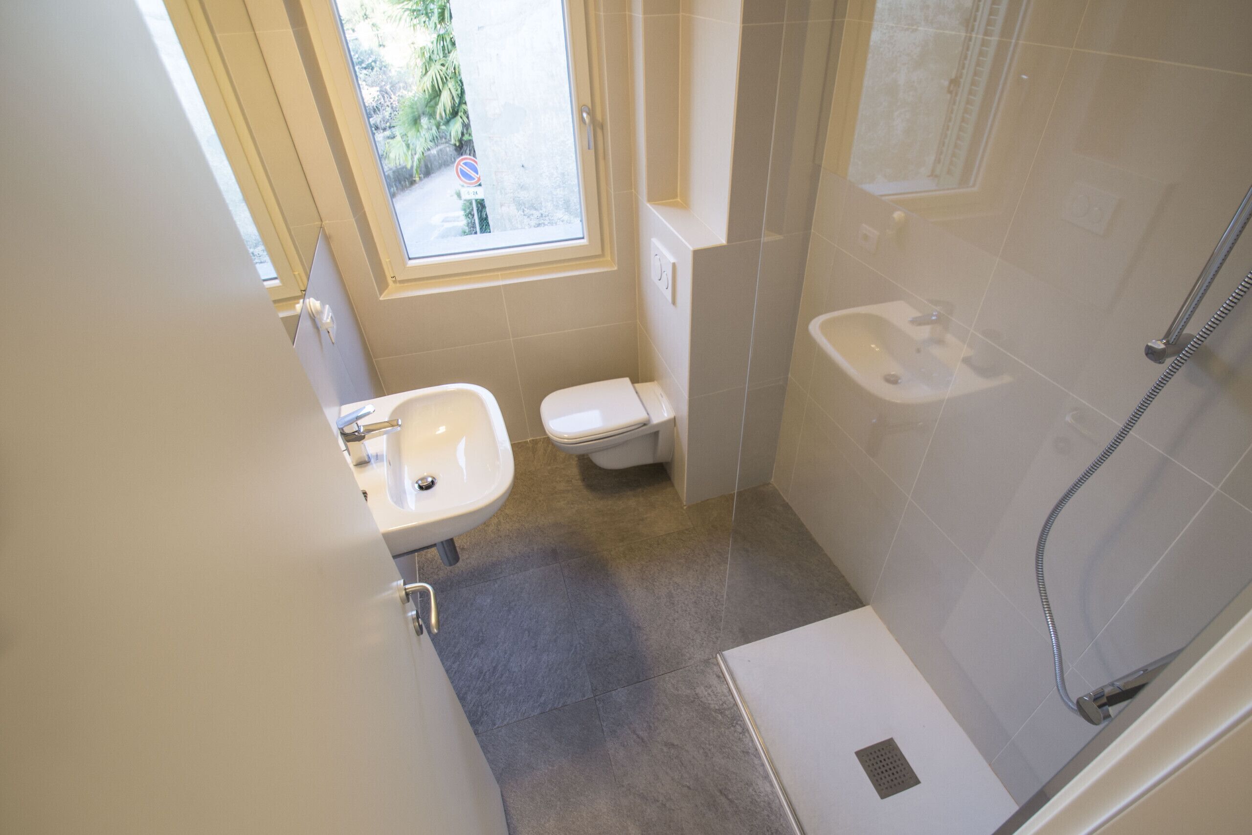 A small bathroom with a toilet, sink, and shower.