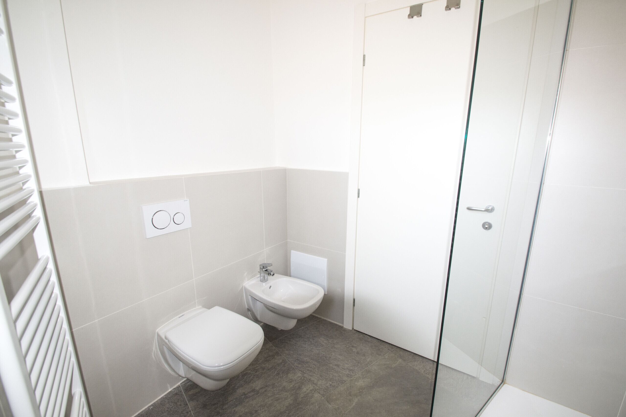 Une petite salle de bain moderne équipée de toilettes, d’un bidet et d’une douche à parois de verre.