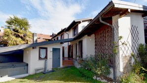A two-story house with a covered patio, a small garden, and a visible garage.
